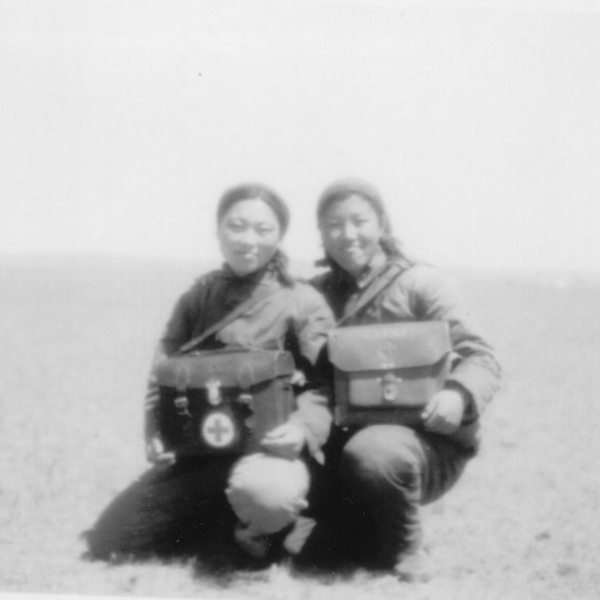 Black and white photo of two young Asian ladies kneeling and smiling while holding their doctors bags